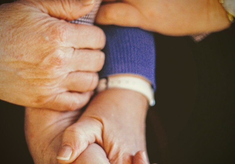 person in blue long sleeve shirt holding babys hand